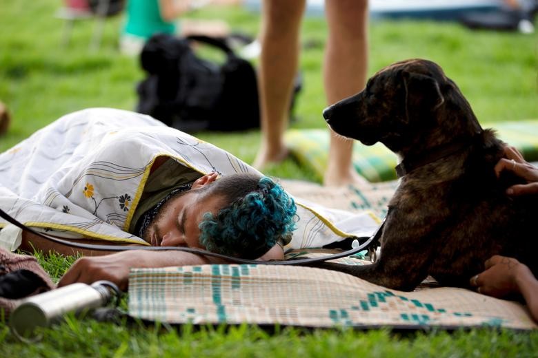 A man rests next to a dog at a protest campsite, set up as part of on-going protests against Israeli Prime Minister Benjamin Netanyahu's alleged corruption and his government's handling of the coronavirus crisis, at a park near Netanyahu's residence in Jerusalem. REUTERS/Ronen Zvulun
